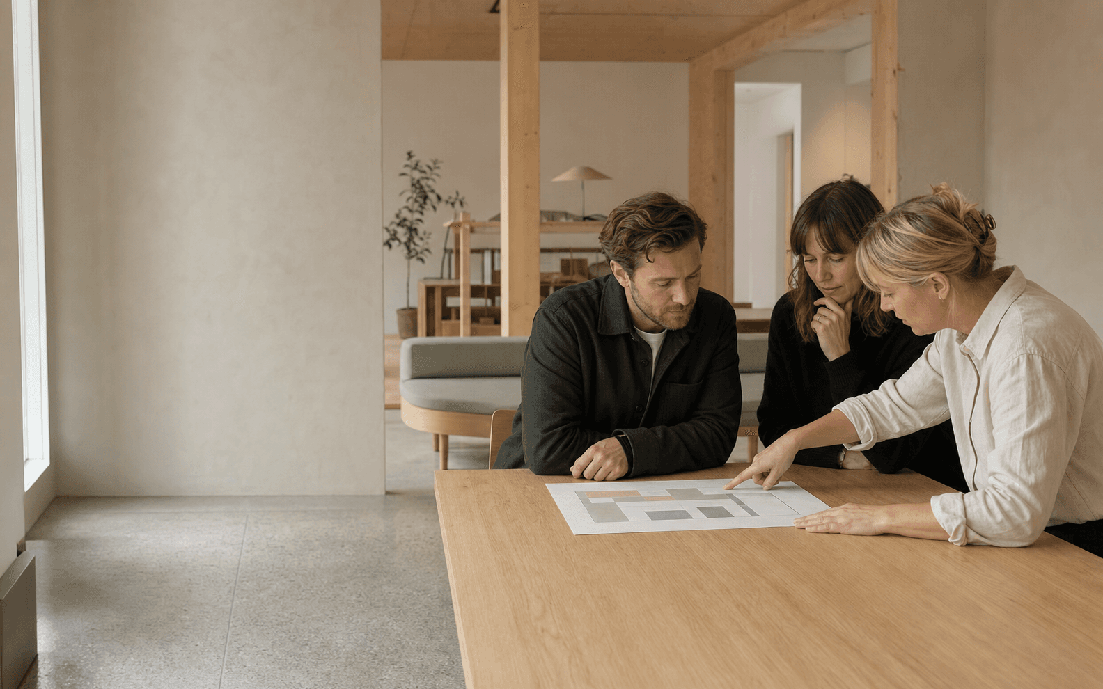 Tre kollegor arbetar tillsammans kring ett gemensamt planeringsunderlag
